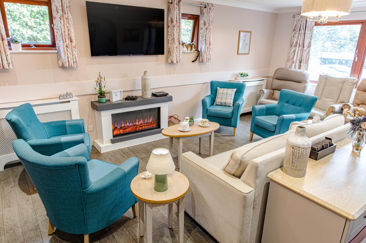 communal area with multiple blue and cream chairs in a circle with a lit fireplace